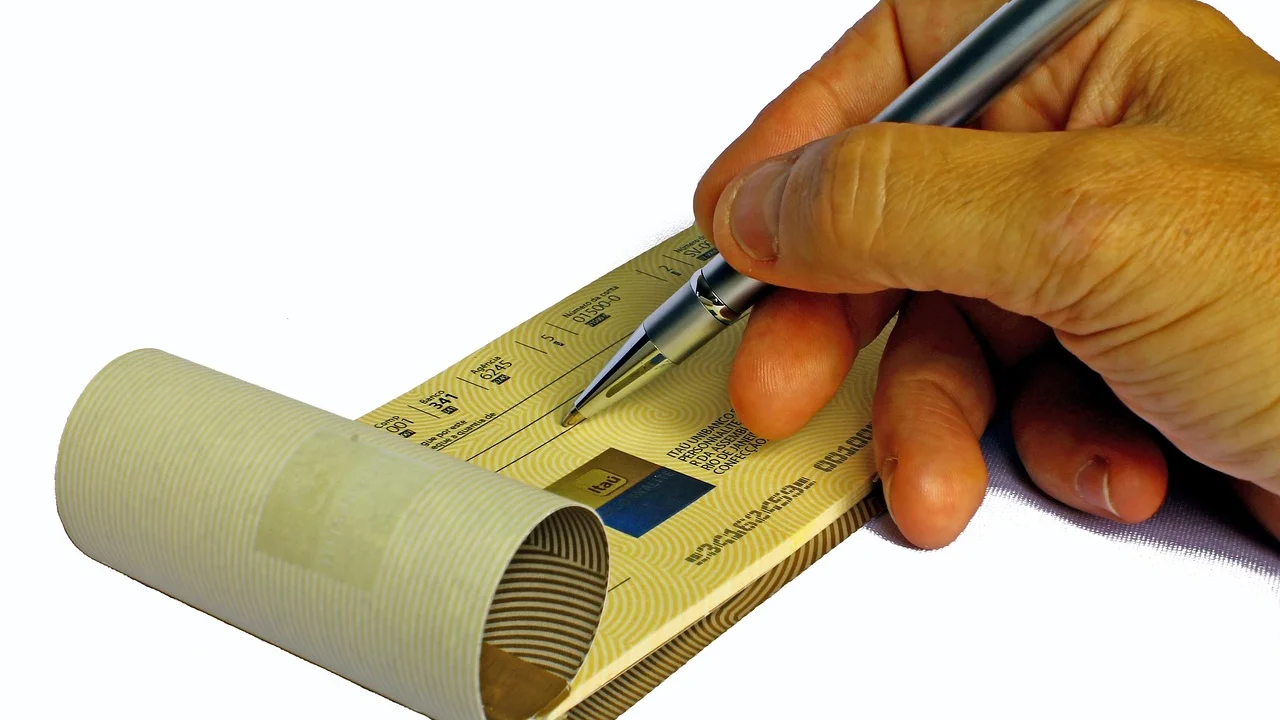 Cheque preenchido sobre uma mesa com caneta ao lado