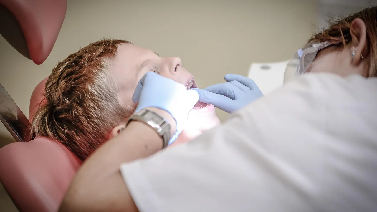 Cirurgião-dentista realiza avaliação em consultório odontológico.