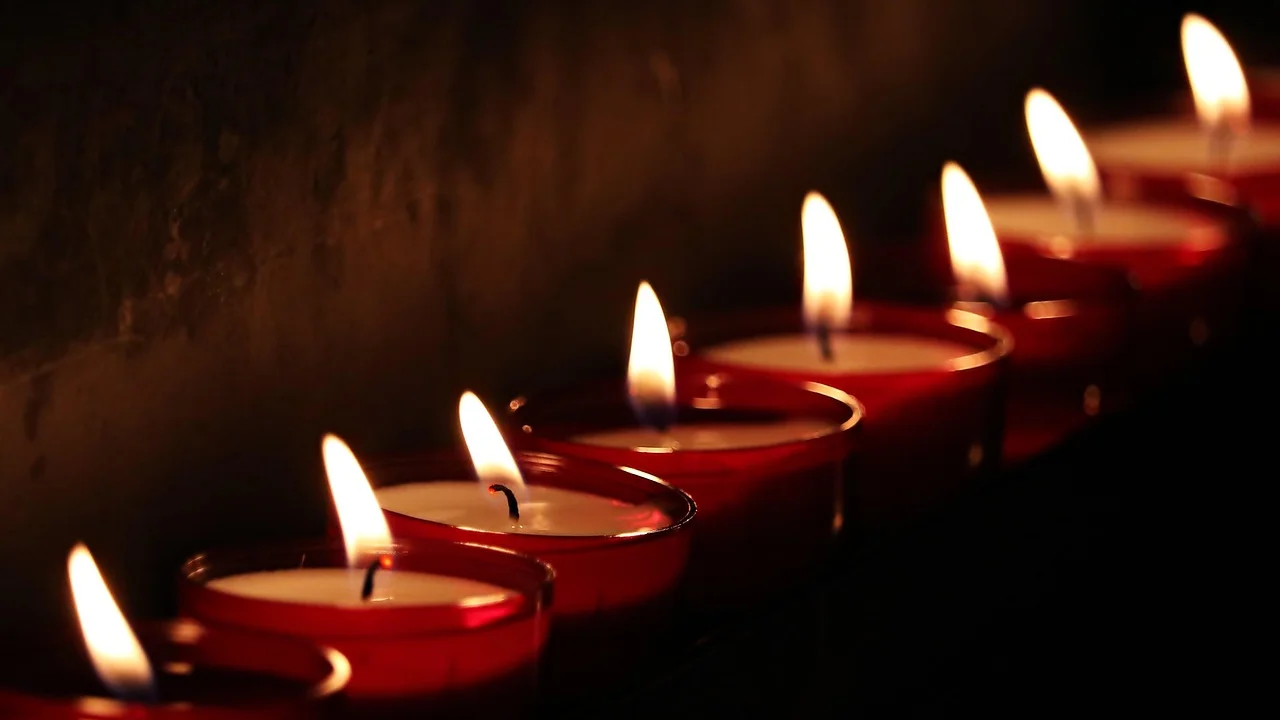 Mãos segurando uma vela durante uma oração silenciosa.