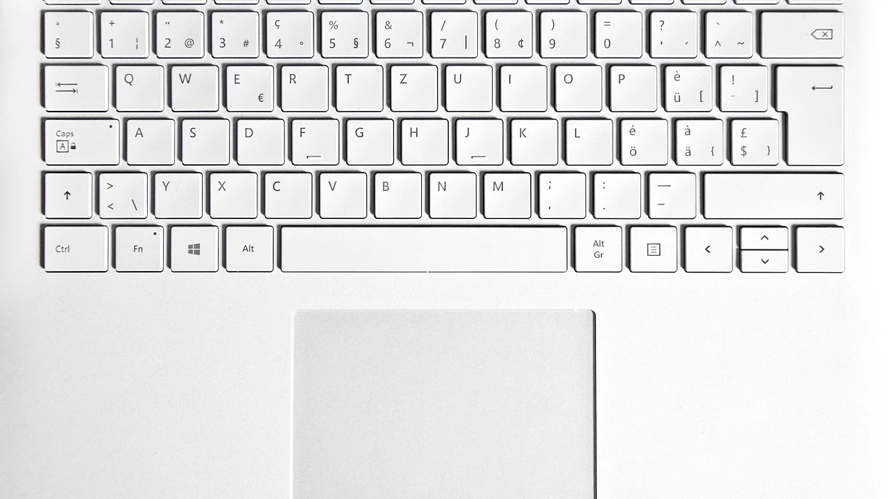 Técnico avaliando a área do touchpad em um notebook desligado.