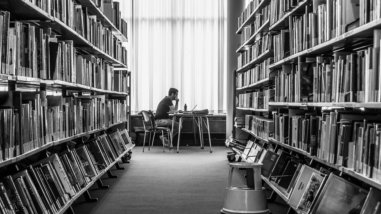Estudante consulta livros e artigos para organizar a pesquisa.