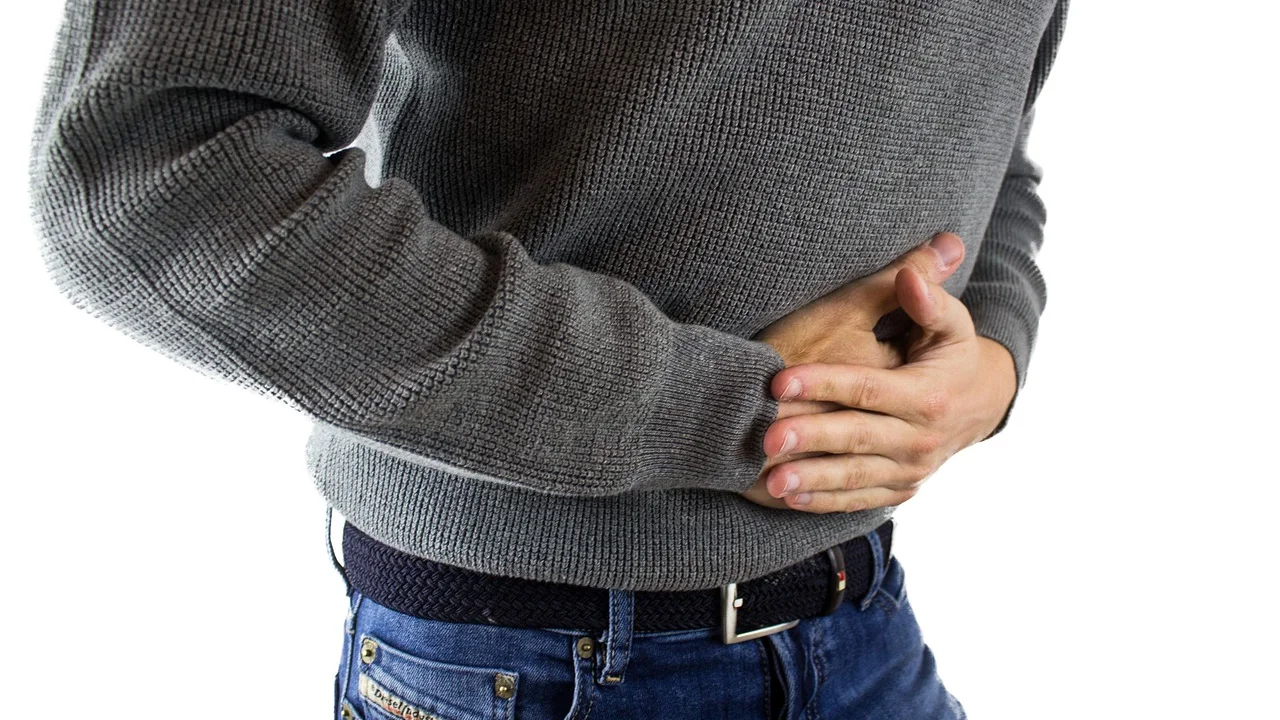 Pessoa com desconforto abdominal em ambiente doméstico