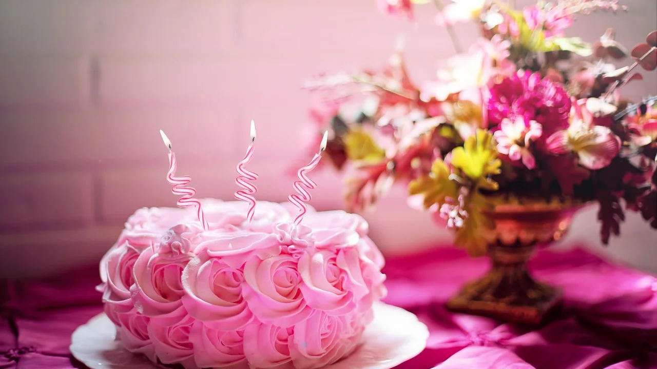 Detalhes de flores e doces em mesa de aniversário.