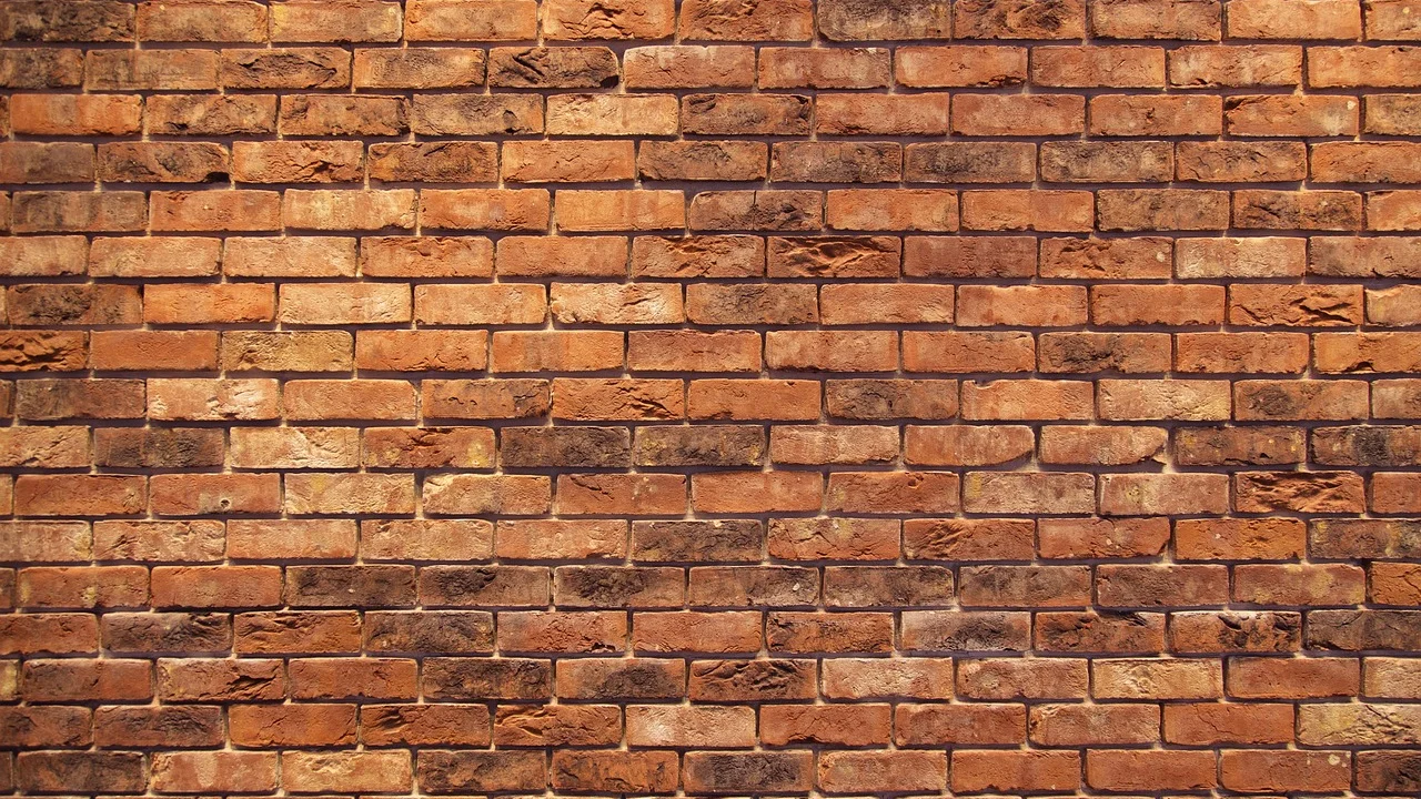 Muro de alvenaria em construção com pilares estruturais.