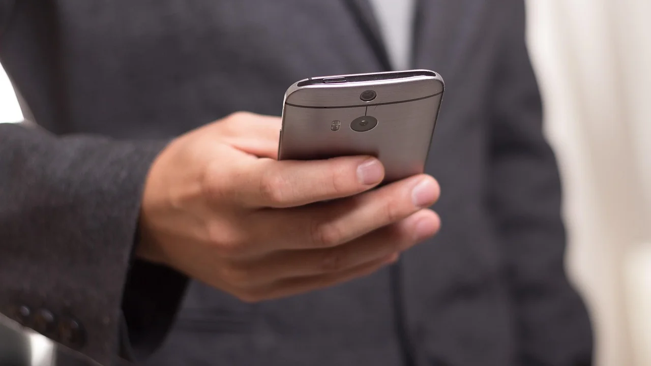 Tela de celular com lista de conversas em aplicativo de mensagens